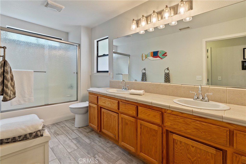 11625 Cenegal Road Atascadero, CA 93422 - Photo 27 of 65 The generous main bathroom offers tile floors, tub/shower combination with rain glass doors and large double sink vanity.