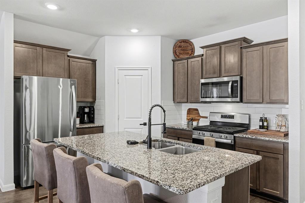 706 Spur Ridge Princeton, TX 75407 - Photo 16 of 38 a kitchen with granite countertop a sink stove and refrigerator
