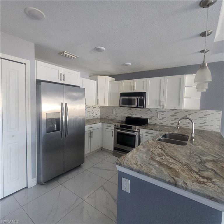 131 Gilbert Avenue South Lehigh Acres, FL 33973 - Photo 3 of 13 a kitchen with stainless steel appliances granite countertop a refrigerator a stove a sink a microwave and a refrigerator