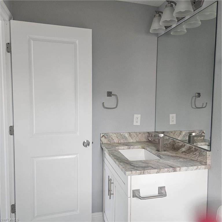 131 Gilbert Avenue South Lehigh Acres, FL 33973 - Photo 10 of 13 a bathroom with a granite countertop sink and a mirror