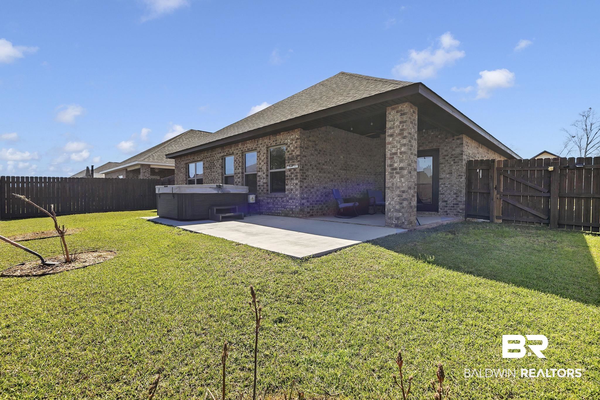 1547 Kairos Loop Foley, AL 36535 - Photo 39 of 55 Back of house with a patio, brick siding, a fenced backyard, and a hot tub