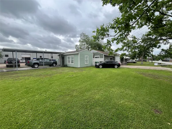 a view of a house with a big yard and large trees