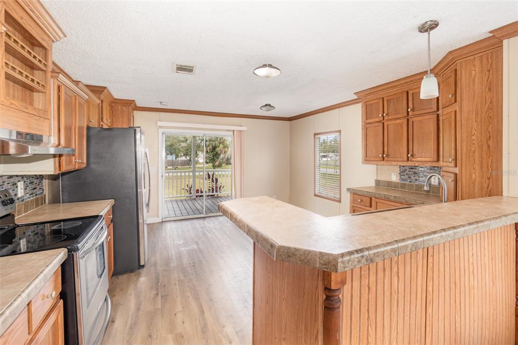25542 Mathew Street Christmas, FL 32709 - Photo 6 of 18 a kitchen with stainless steel appliances granite countertop a refrigerator a stove and a sink with wooden floor
