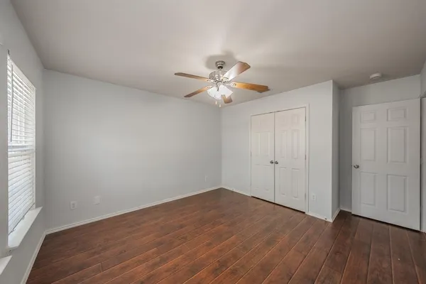 a view of a room with wooden floor and a ceiling fan