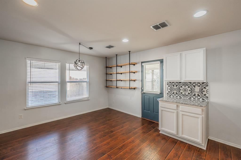 712 Grant Street Burleson, TX 76028 - Photo 13 of 28 a kitchen with granite countertop wooden floors and white cabinets