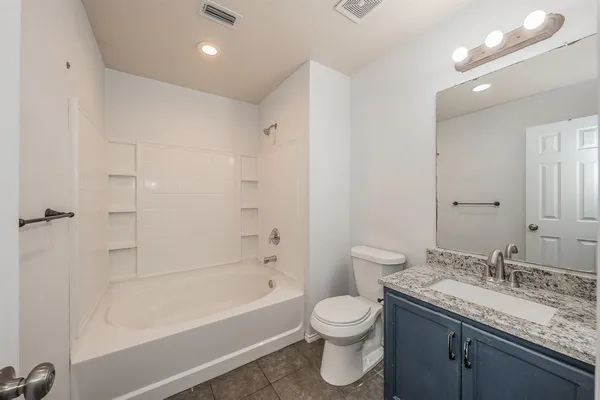 a bathroom with a granite countertop sink a toilet and bathtub