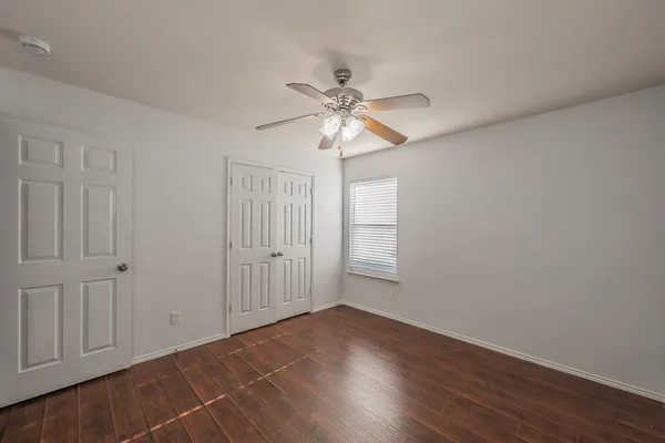 a view of an empty room with a window and wooden floor