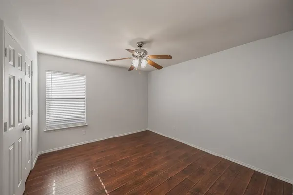 an empty room with a window and a fan