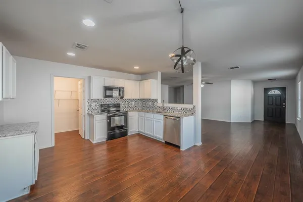 a large kitchen with granite countertop a large counter top a sink stainless steel appliances and cabinets
