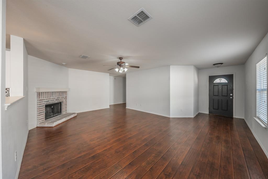 712 Grant Street Burleson, TX 76028 - Photo 6 of 28 an empty room with wooden floor fireplace and windows