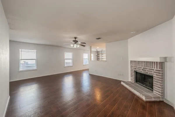 an empty room with wooden floor fireplace and windows