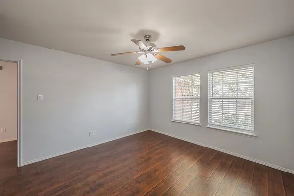 a view of an empty room with window and wooden floor