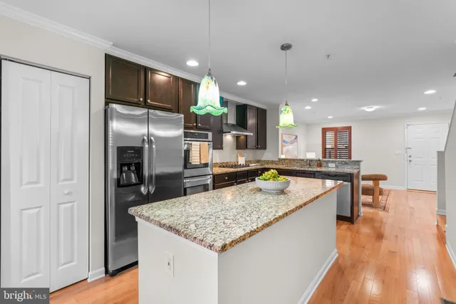 a kitchen with stainless steel appliances granite countertop a refrigerator a stove and a sink