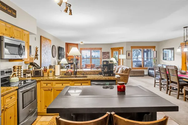 a kitchen with stainless steel appliances granite countertop a stove and a view of living room