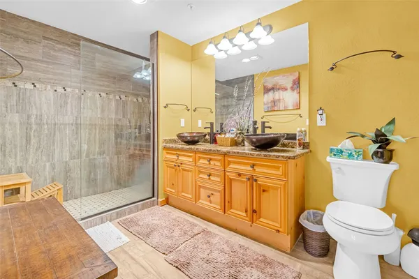 a bathroom with a granite countertop sink a toilet a mirror and shower