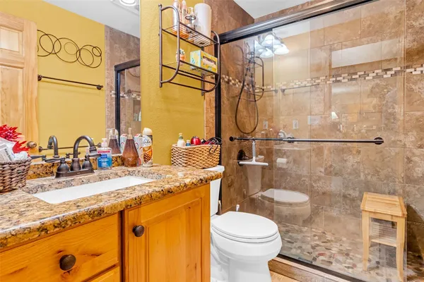 a bathroom with a granite countertop sink a toilet and shower
