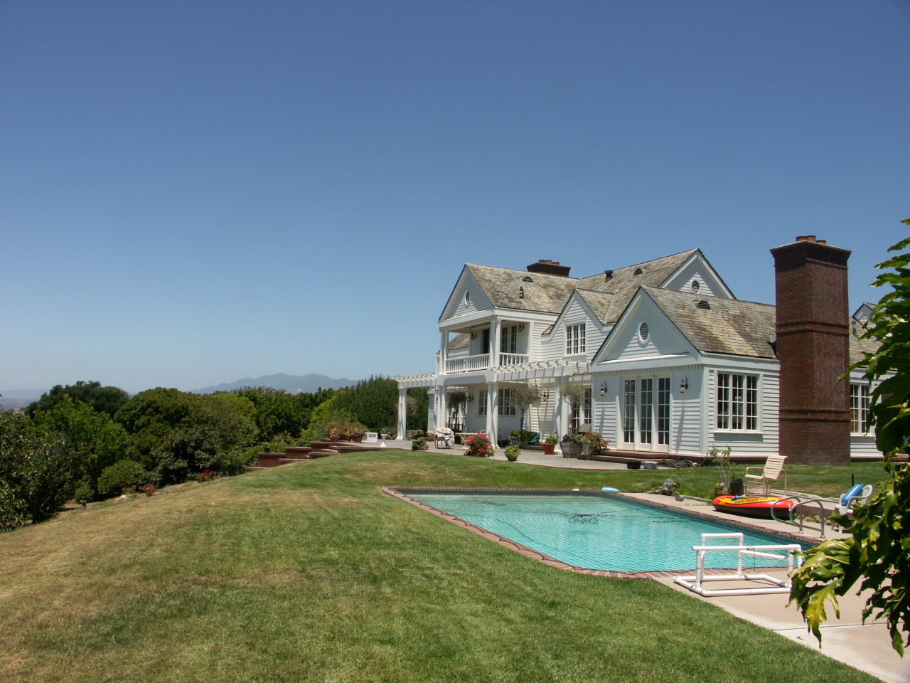 Undisclosed Address Hope Ranch, CA 93110 - Photo 13 of 17 a front view of a house with garden and swimming pool