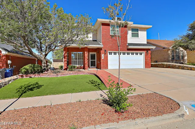a front view of a house with a yard and potted plants