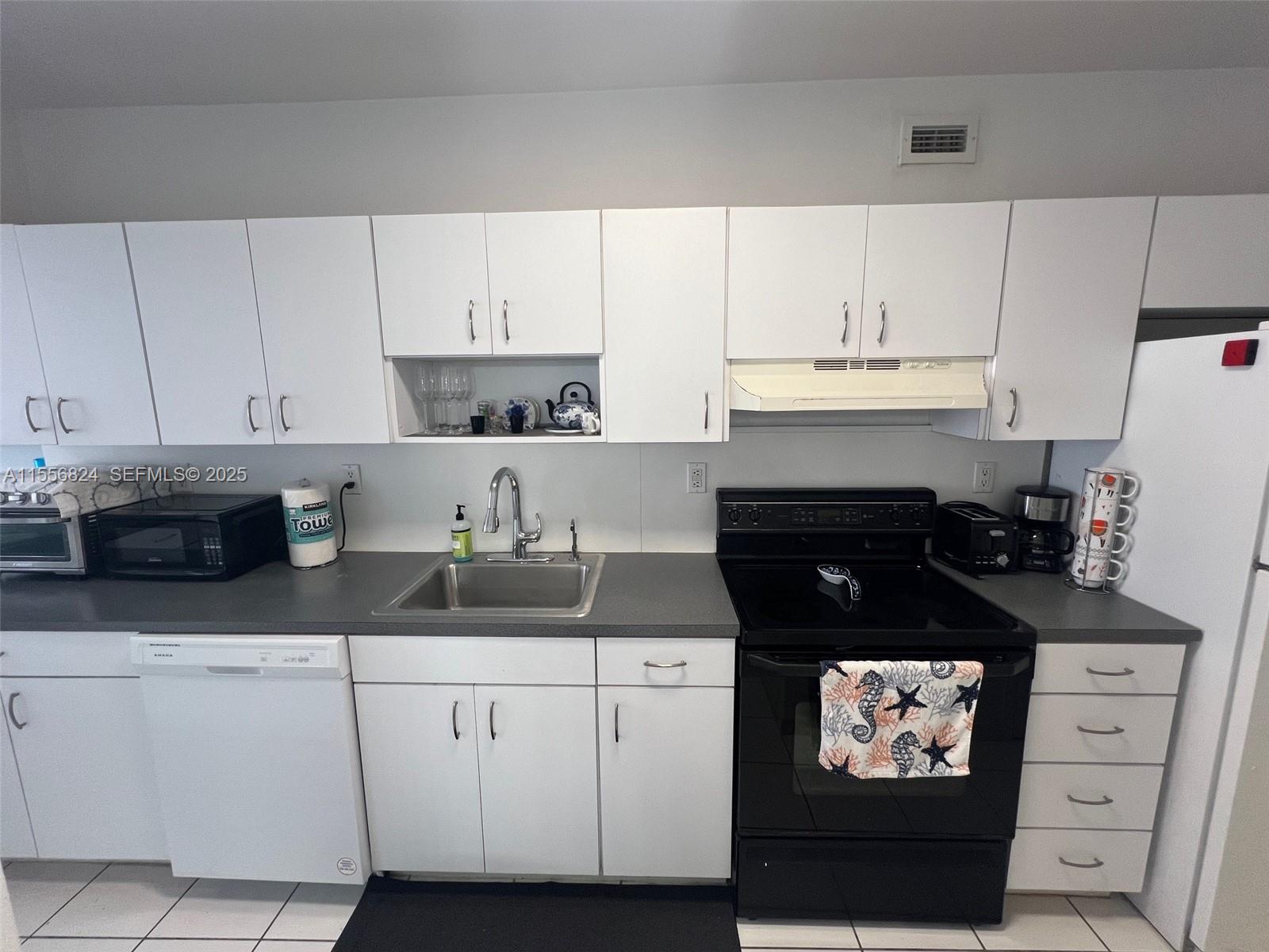 100 Lincoln Road, Unit 1126 Miami Beach, FL 33139 - Photo 16 of 52 a kitchen with white cabinets and black appliances