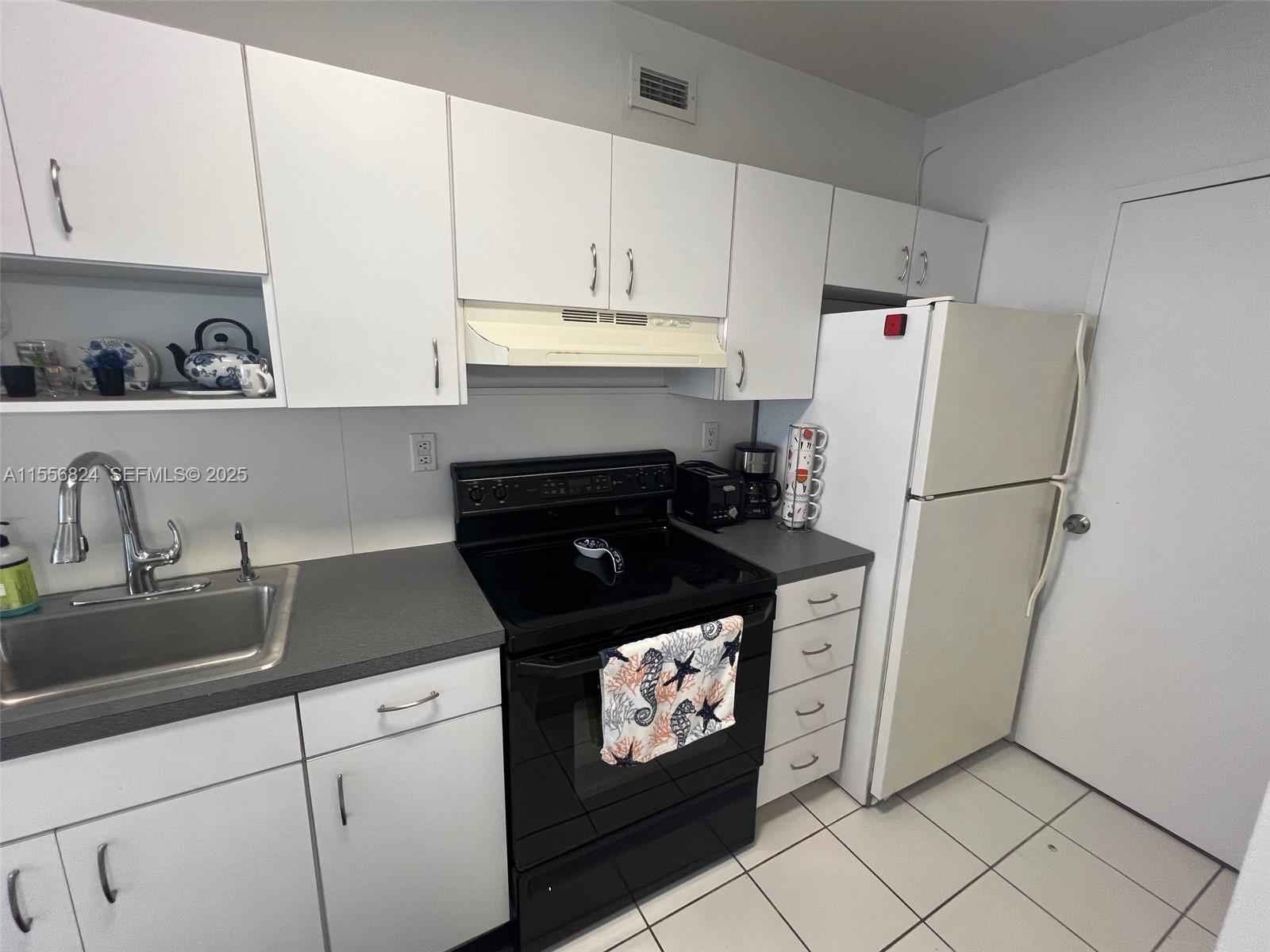 100 Lincoln Road, Unit 1126 Miami Beach, FL 33139 - Photo 17 of 52 a kitchen with granite countertop white cabinets and refrigerator