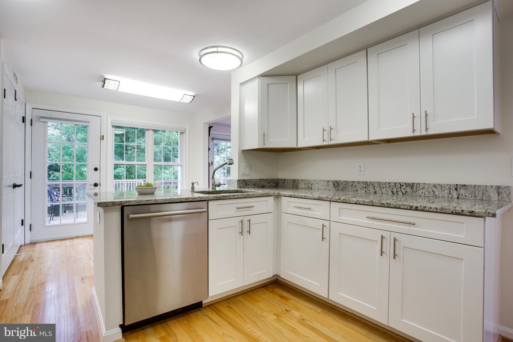 1511 Deer Point Way Reston, VA 20194 - Photo 3 of 30 a kitchen with granite countertop white cabinets white appliances a sink and dishwasher with wooden floor