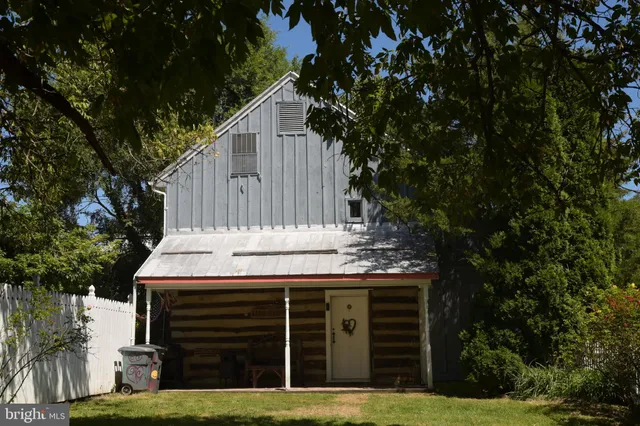 a view of a house with large tree and wooden fence