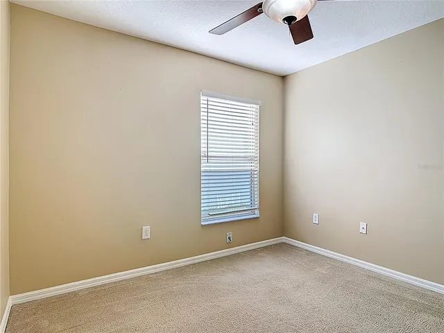an empty room with a chandelier fan and closet area