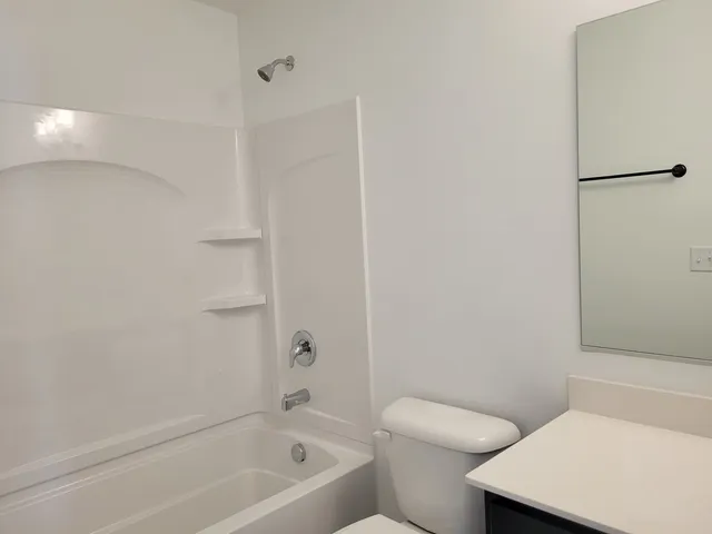 a white toilet sitting next to a bath tub