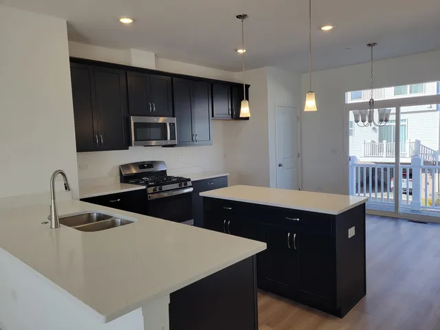 a kitchen with stainless steel appliances a sink a stove a refrigerator cabinets and a dining table