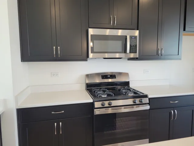 a kitchen with stainless steel appliances a stove a microwave a sink and cabinets