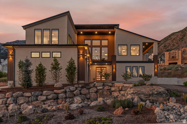 1445 Jacob Road Sandy, UT 84092 - Photo 62 of 65 Modern architectural design featuring varied rooflines, extensive window placements, and a natural stone retaining wall
