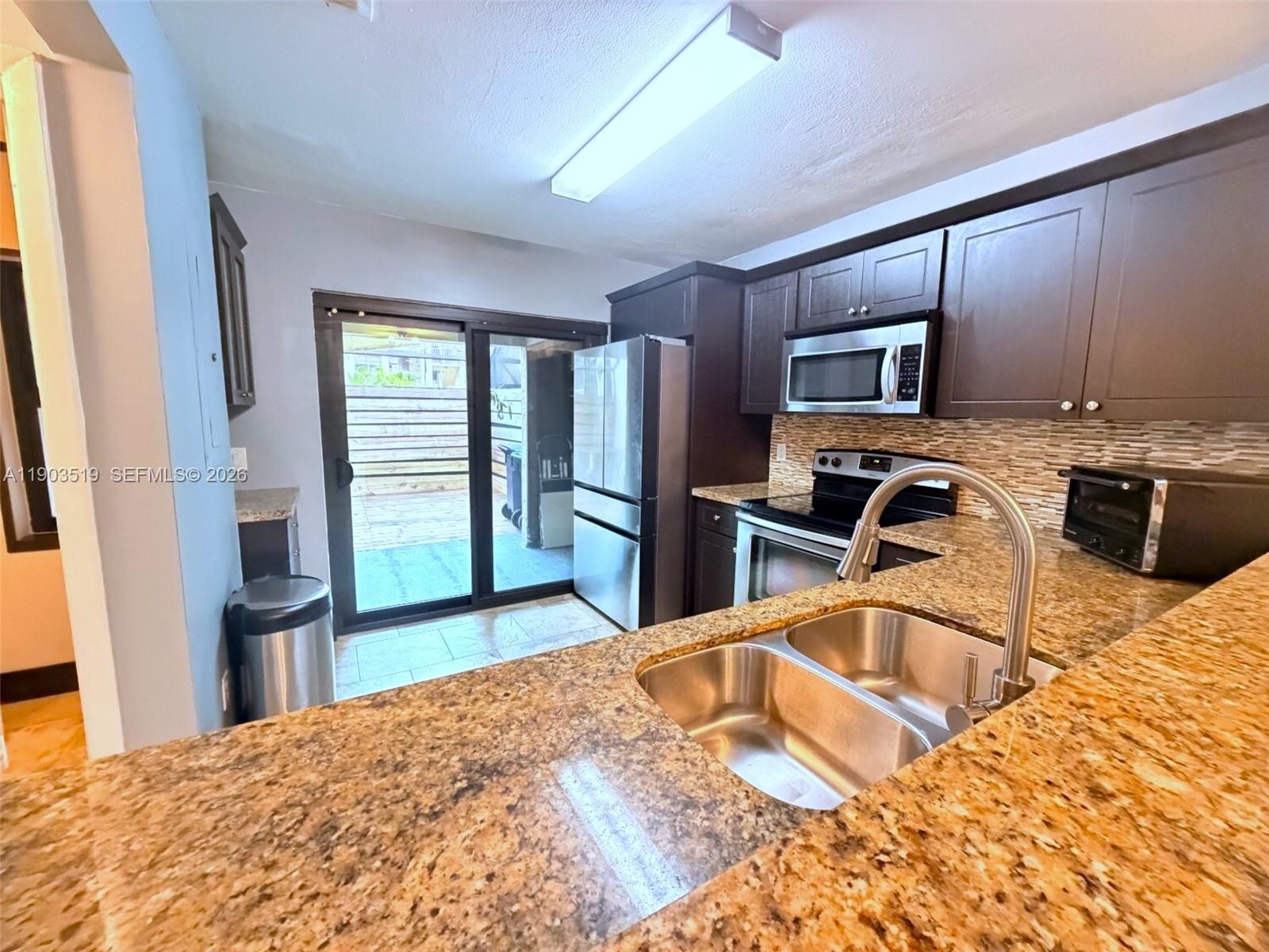 10515 Southwest 153rd Court, Unit 3 Miami, FL 33196 - Photo 11 of 32 a kitchen with stainless steel appliances granite countertop a sink refrigerator and microwave