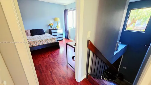 a bedroom with a bed and dresser with wooden floor