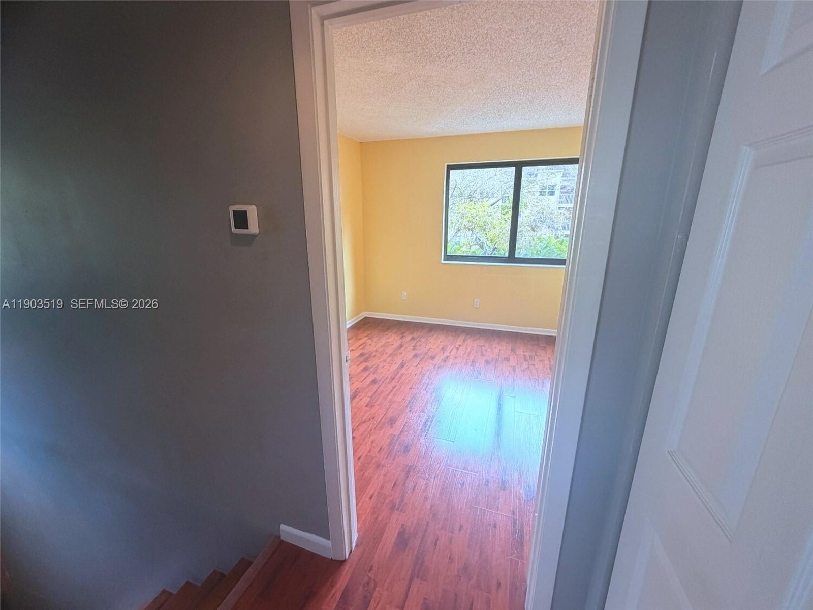 10515 Southwest 153rd Court, Unit 3 Miami, FL 33196 - Photo 21 of 32 an empty room with wooden floor and windows