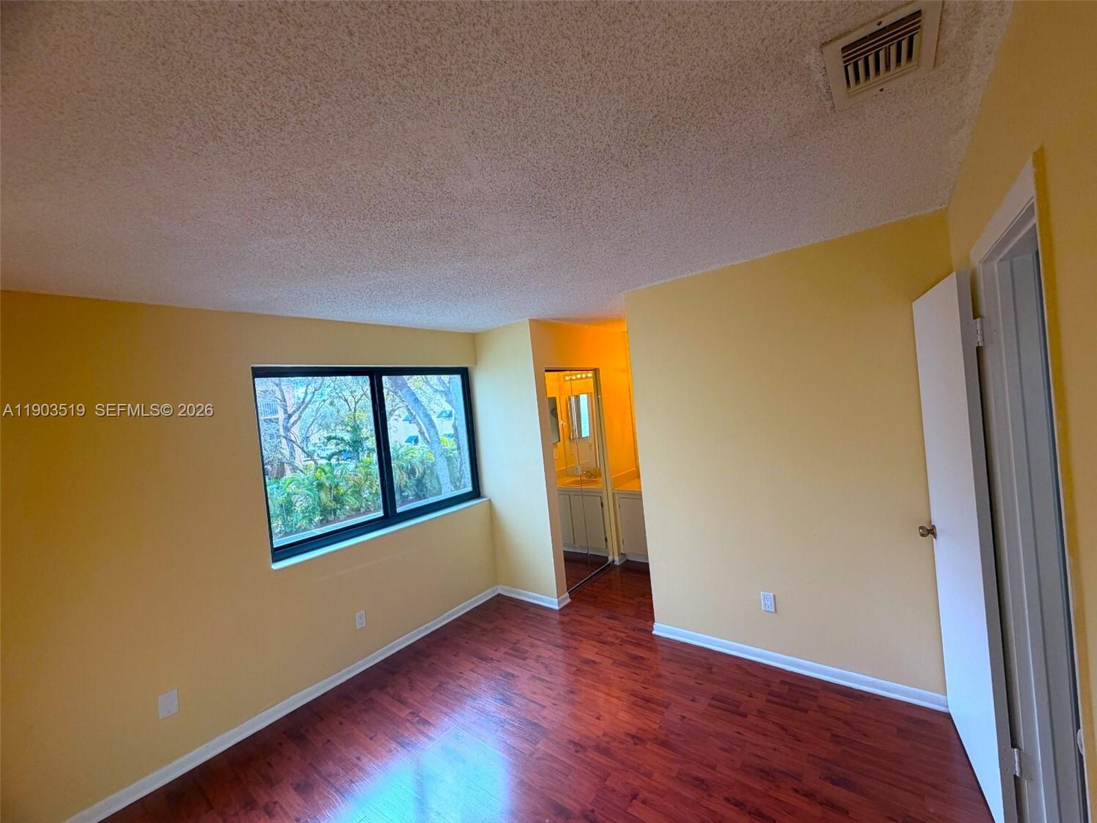 10515 Southwest 153rd Court, Unit 3 Miami, FL 33196 - Photo 22 of 32 a view of an empty room with wooden floor and a window
