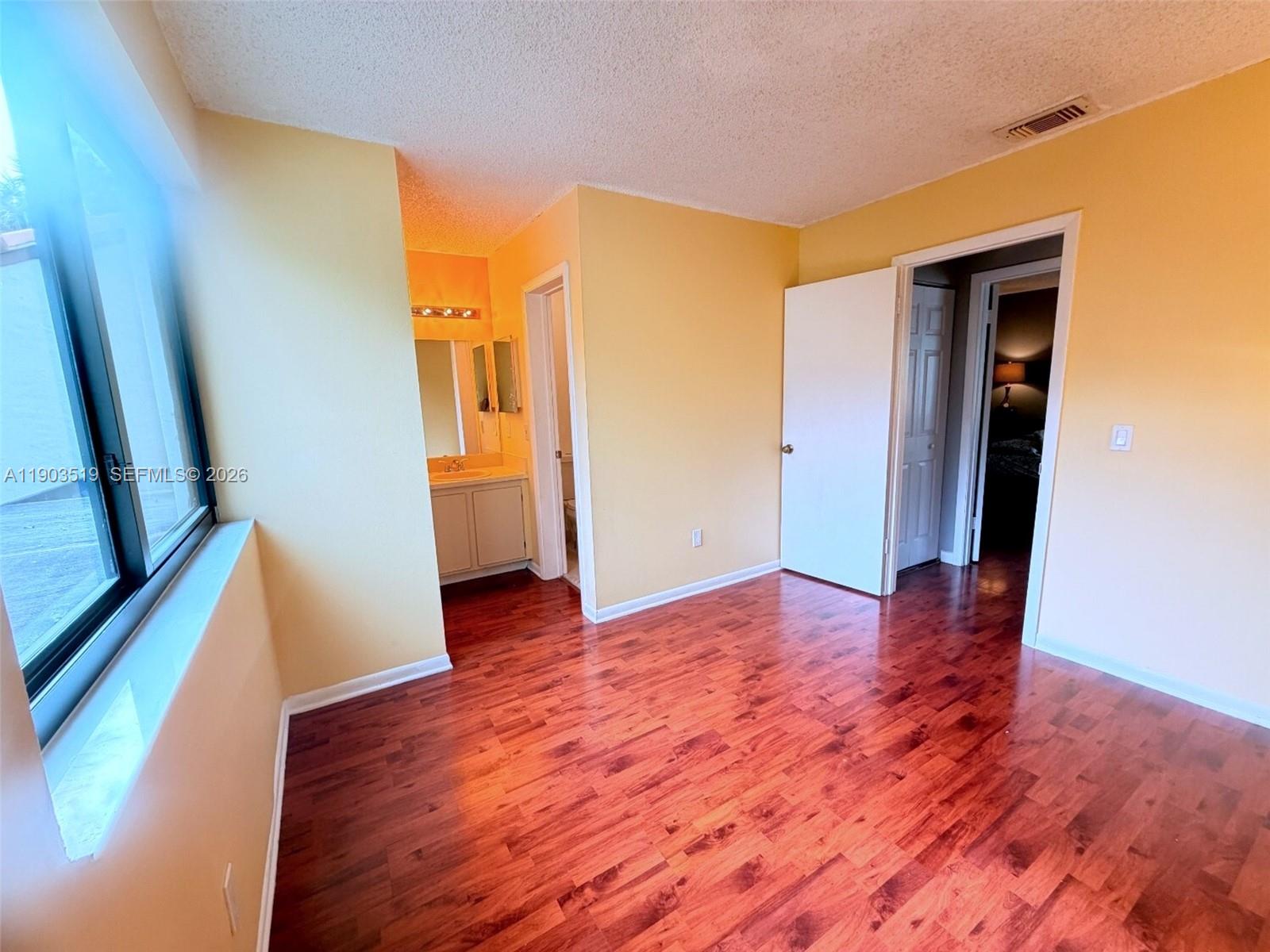 10515 Southwest 153rd Court, Unit 3 Miami, FL 33196 - Photo 26 of 32 a view of an empty room with wooden floor and a window
