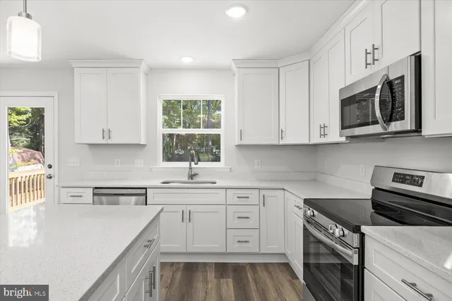 a kitchen with stainless steel appliances granite countertop white cabinets granite counter tops and a window