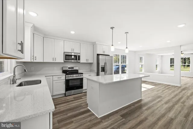 a kitchen with granite countertop a stove top oven a sink dishwasher and a refrigerator with wooden floor