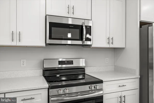 a kitchen with stainless steel appliances granite countertop white cabinets and a stove top oven