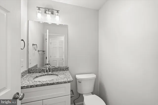 a bathroom with a granite countertop sink toilet and mirror