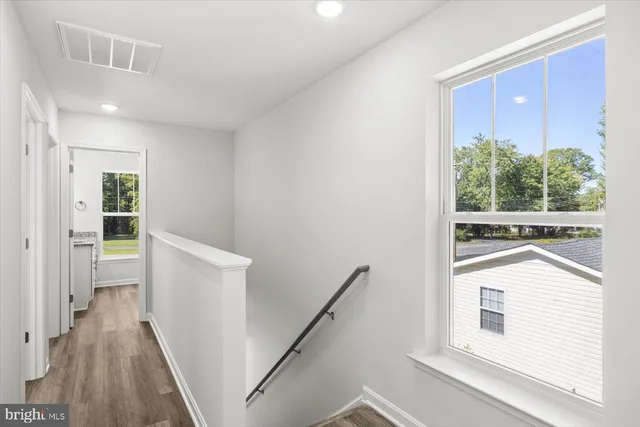 a view of a hallway with wooden floor and staircase