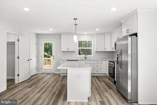 a kitchen with a refrigerator a sink and dishwasher with wooden floor