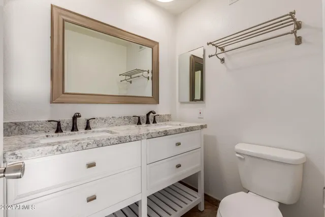 a bathroom with a granite countertop toilet sink and mirror