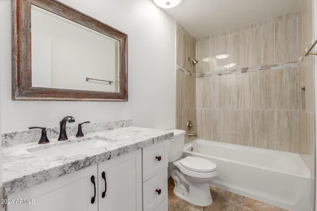a bathroom with a granite countertop sink toilet a large mirror a bathtub and shower