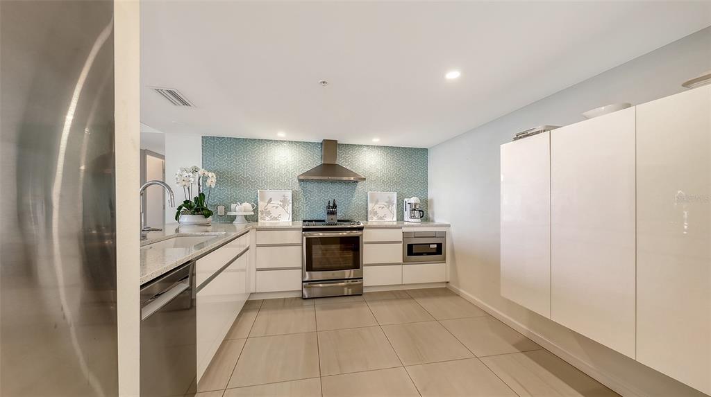 11 Sunset Drive, Unit 501 Sarasota, FL 34236 - Photo 18 of 63 a large white kitchen with a sink and dishwasher a stove top oven with wooden floor