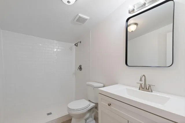 a bathroom with a toilet sink vanity and mirror