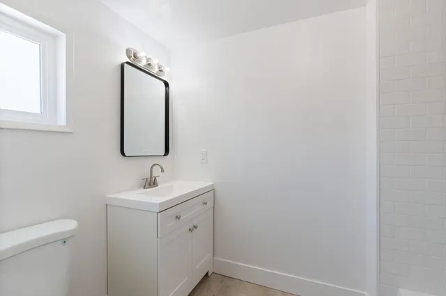 a bathroom with a toilet sink vanity and mirror
