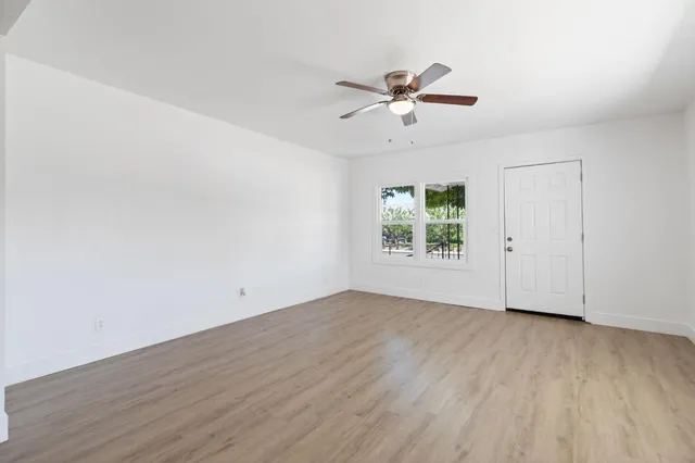 a view of an empty room with wooden floor and a window