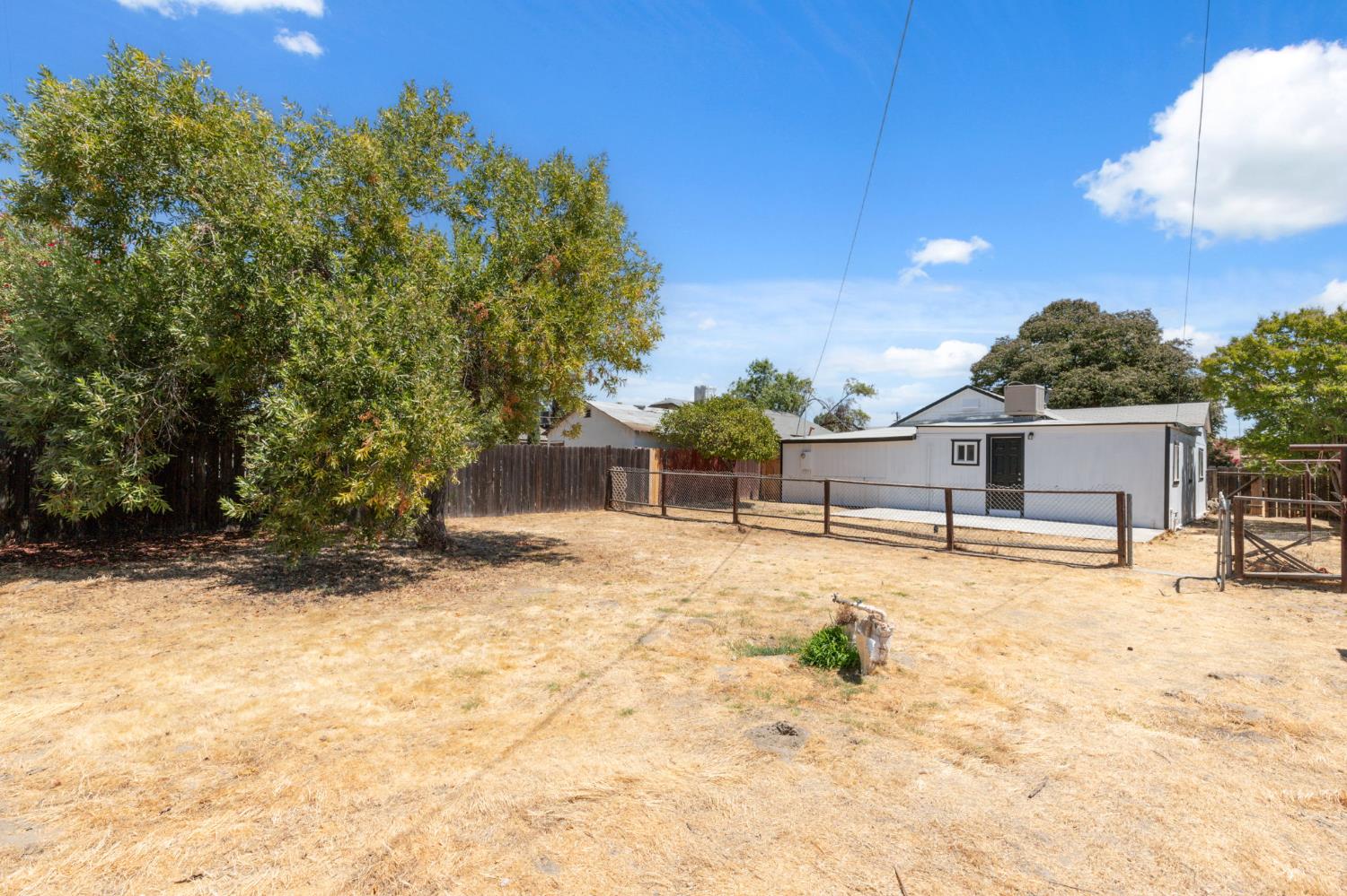 575 South 8th Street Kerman, CA 93630 - Photo 20 of 21 a tall yellow house with a yard in front of it