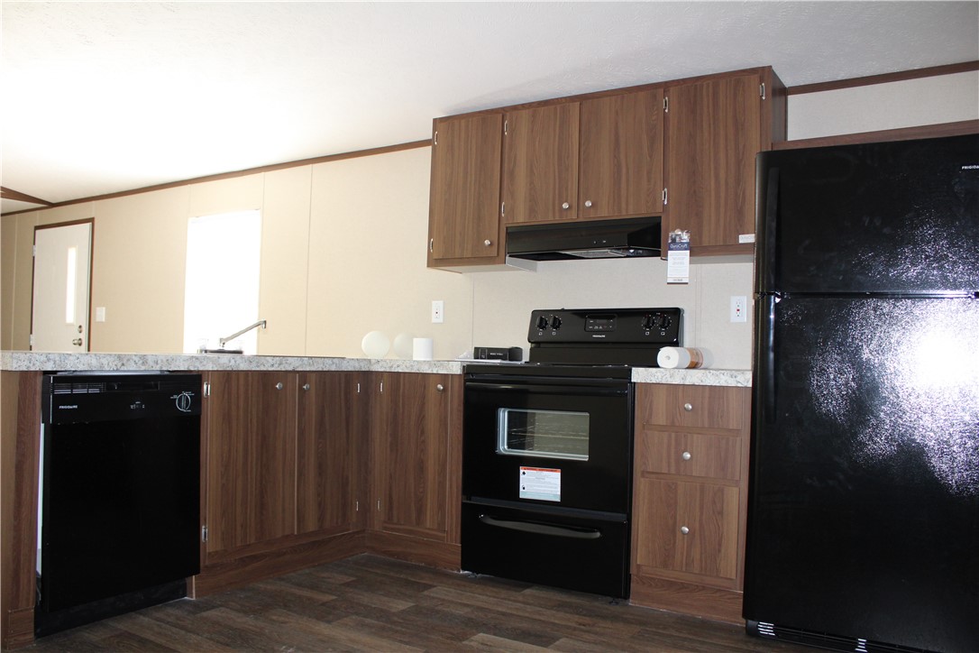 119 Royal Street Taylor, TX 76574 - Photo 11 of 18 a kitchen with granite countertop wooden cabinets and black appliances